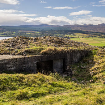 A concrete box-shaped building in a green landscape