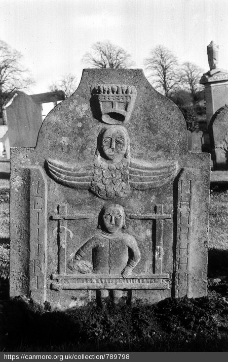 Black and white photo of a headstone in a graveyard depicting a person working at a loom and an angel overhead