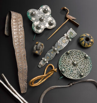 Photo of assorted precious items from the Galloway Hoard, including a bird-shaped pin, brooches and flattened arm rings