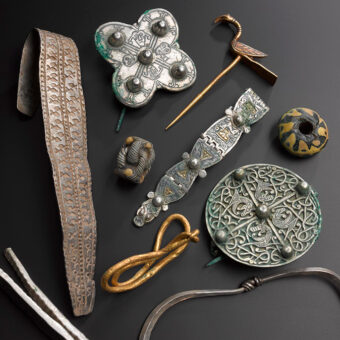 Photo of assorted precious items from the Galloway Hoard, including a bird-shaped pin, brooches and flattened arm rings