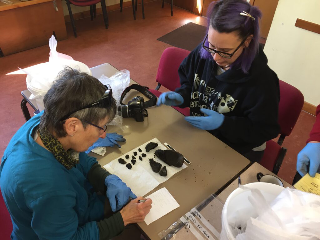 Photo of two people sat at a table cataloguing small finds