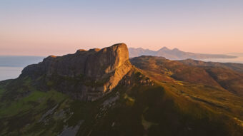 Photo of the summit of a mountain by the sea at sunset