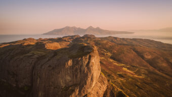 Photo of the summit of a mountain by the sea at sunset
