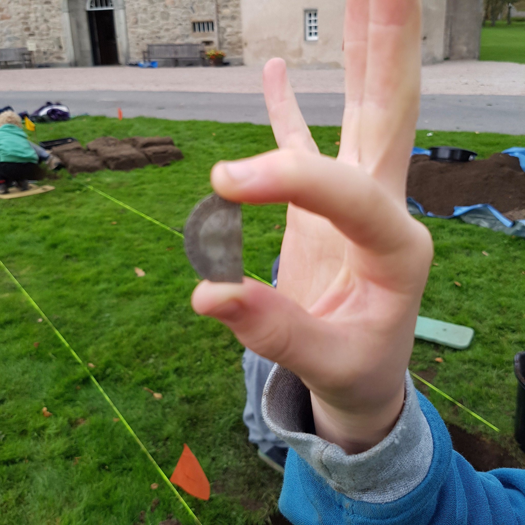Person holding half a coin at a dig site