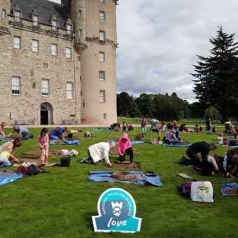 People digging in several small trenches in front of a castle