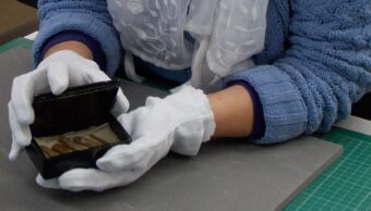 Gloved hands holding something in a small box