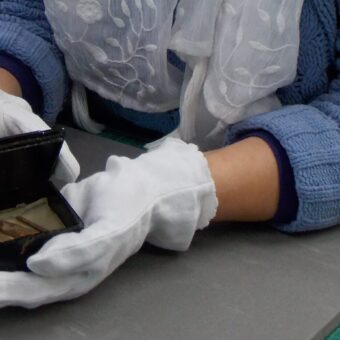 Gloved hands holding something in a small box