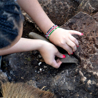 Photo of a person with braids in an archaeological trench digging