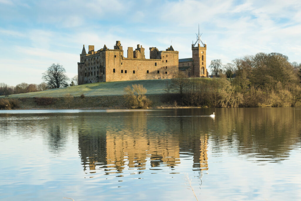 Photo of a medieval stone palace reflected in a loch