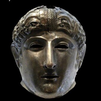 Photo of a carved metal face helmet with curly hair