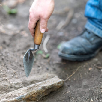 Person using a trowel in a trench