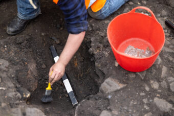 Photograph of someone brushing something in a trench