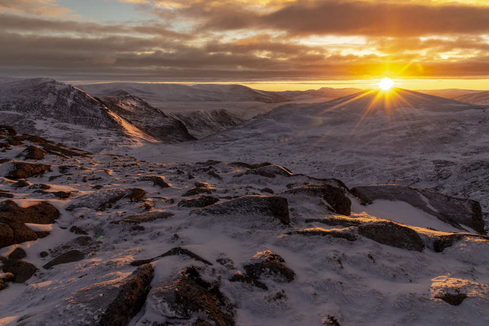 Photo of a snowy mountain landscape at sunset