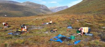 Photo of people in high-visibility clothing excavating in a mountain region