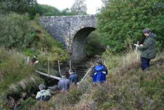 People taking notes near a bridge