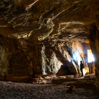 Photo of a person looking into a cave