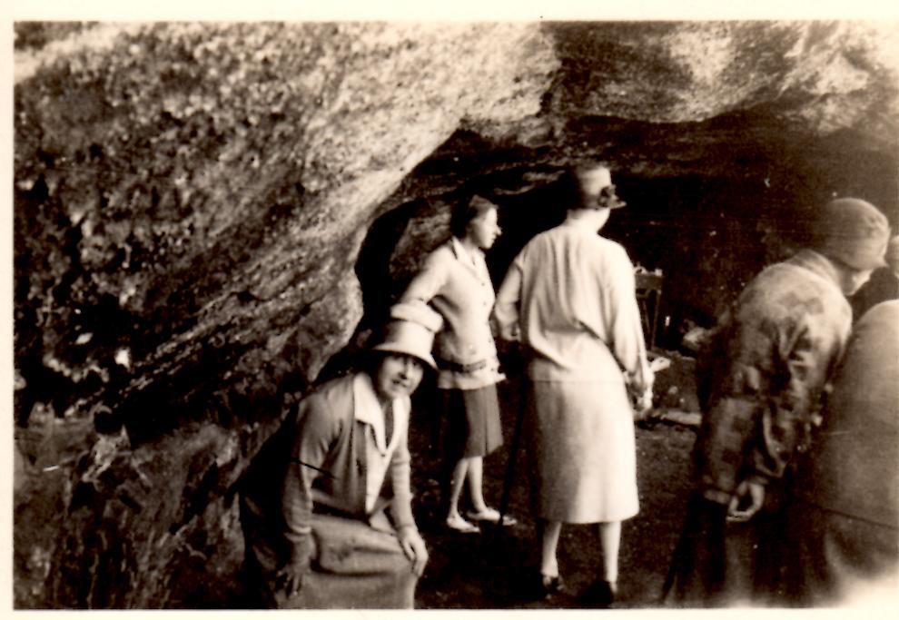 Black and white photo of people in 1930s clothing exploring a cave