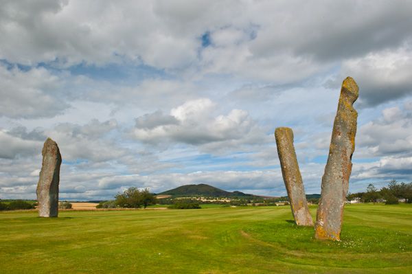 Photo of three standing stones on a fairway with a hill int he background