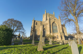 Photo of a cathedral with gravestones in front of it