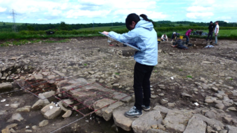 Person drawing while standing at an archaeological site