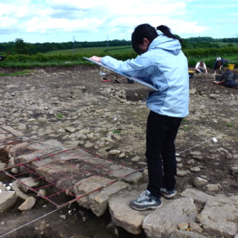 Person drawing while standing at an archaeological site