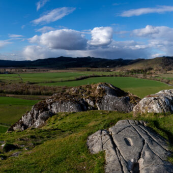 Photo of a stony outcrop looking over a green glen