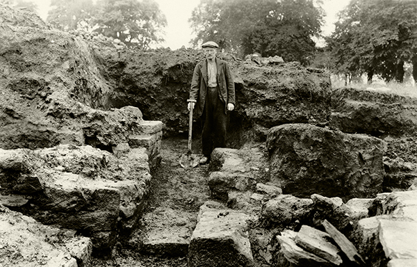 Black and white photo of a person in a large trench