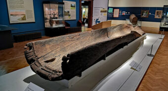 Photo of a wooden logboat on display in a museum gallery