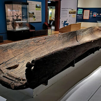 Photo of a wooden logboat on display in a museum gallery