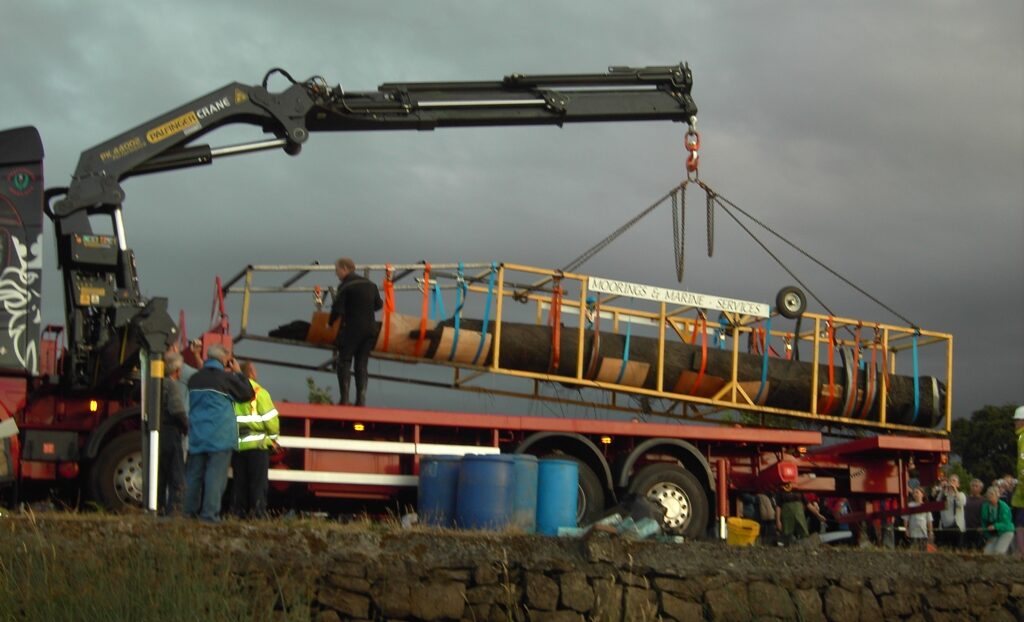 Photo of a prehistoric logboat being lifted by crane onto a flat bed lorry for transportation