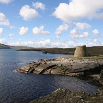 Landscape photo of a stone roundtower on the edge of an island
