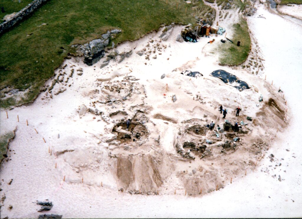 Aerial photo of a large prehistoric site being excavated on a white sandy beach