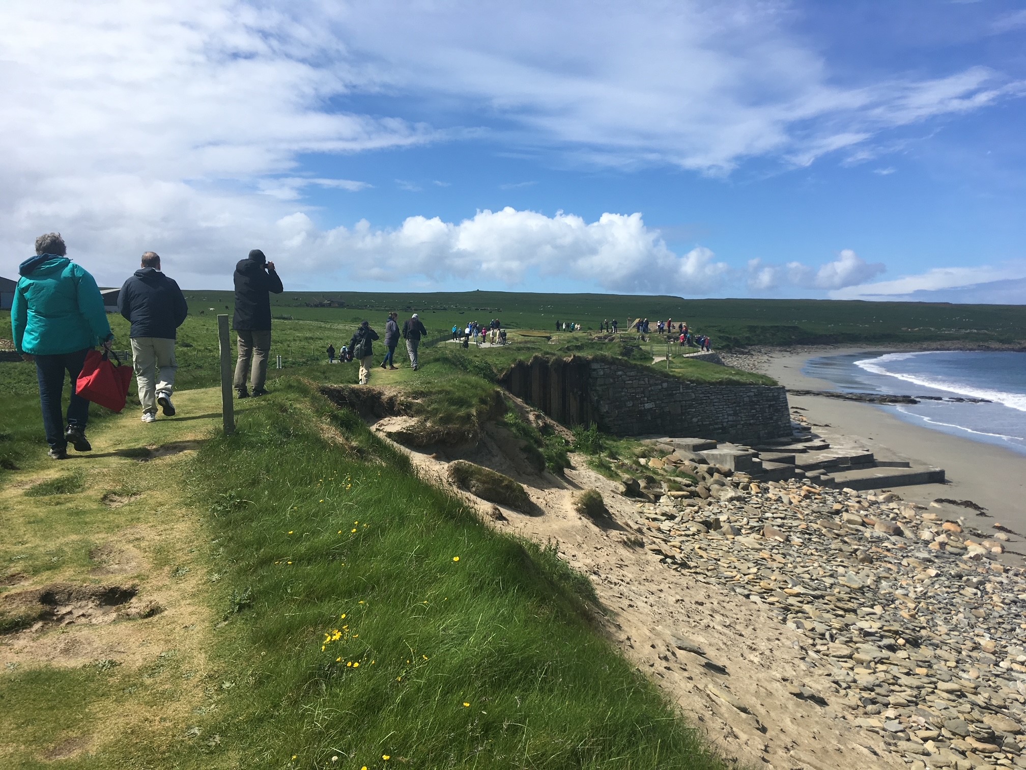Photo of people walking by the edge of a historic site next to the beach