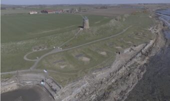 Drone photograph of an old wind turbine and salt pans by the sea