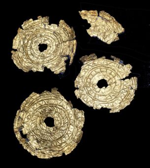 Photo of four ancient gold decorated discs on a black background