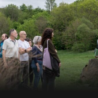 People in a grassy environment listening to a guide