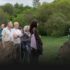 People in a grassy environment listening to a guide