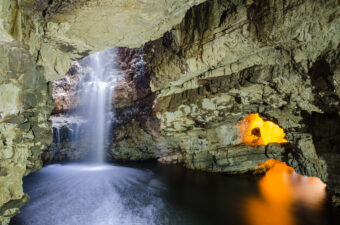 Interior of a large cave with a waterfall