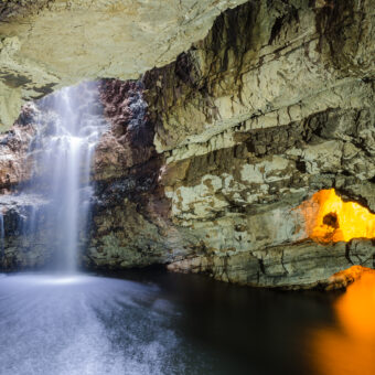 Interior of a large cave with a waterfall