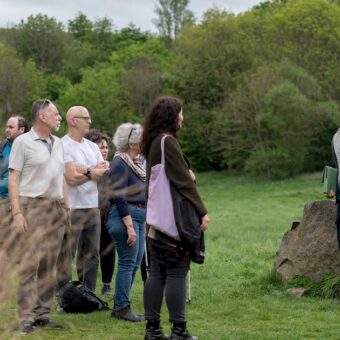 People in a grassy environment listening to a guide
