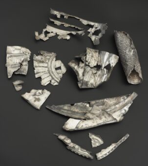 Photo of broken and bent decorated pieces of a sliver platter