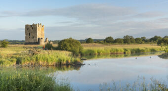 Photo of a square, stone-built tower house on an island in a river