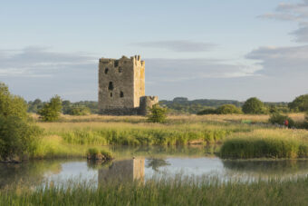 Photo of a square, stone-built tower house on an island in a river