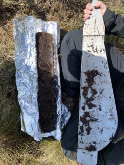 Photo of a person kneeling holding a peat core