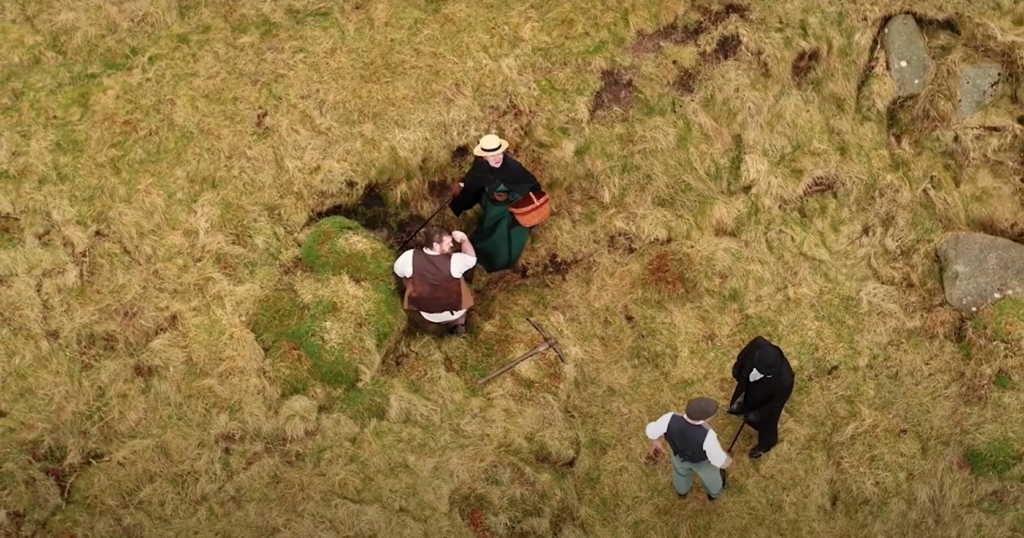 Aerial shot of four people in period costumes in a grassy location