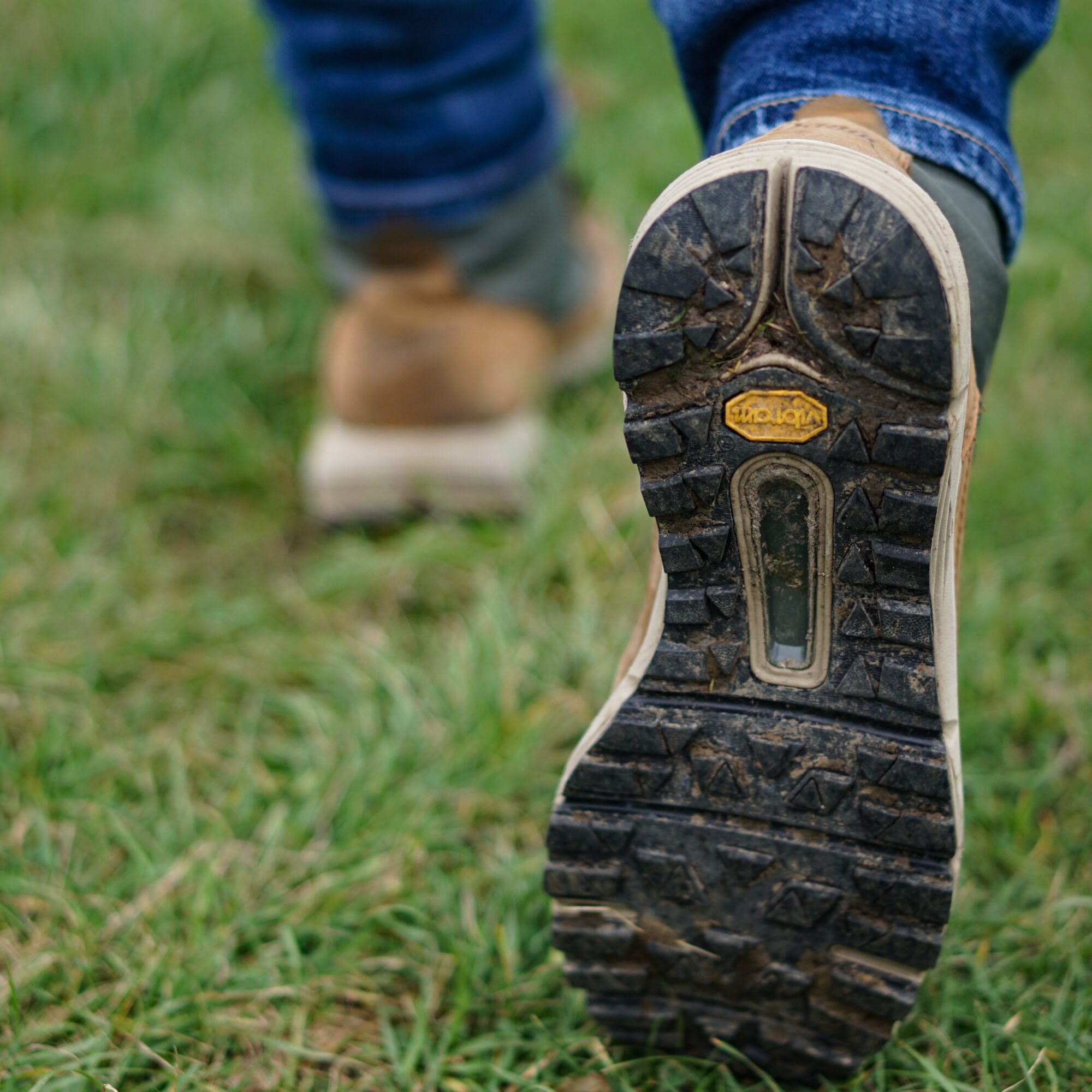 Photo of boots as person is walking - wearing jeans. Walking on grass.