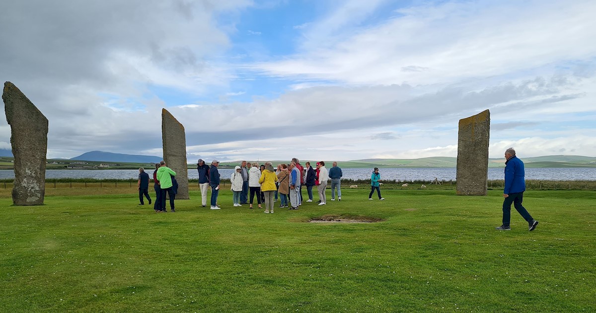 Several people standing around three tall stones