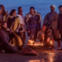 People dressed as Vikings standing around a fire on a beach
