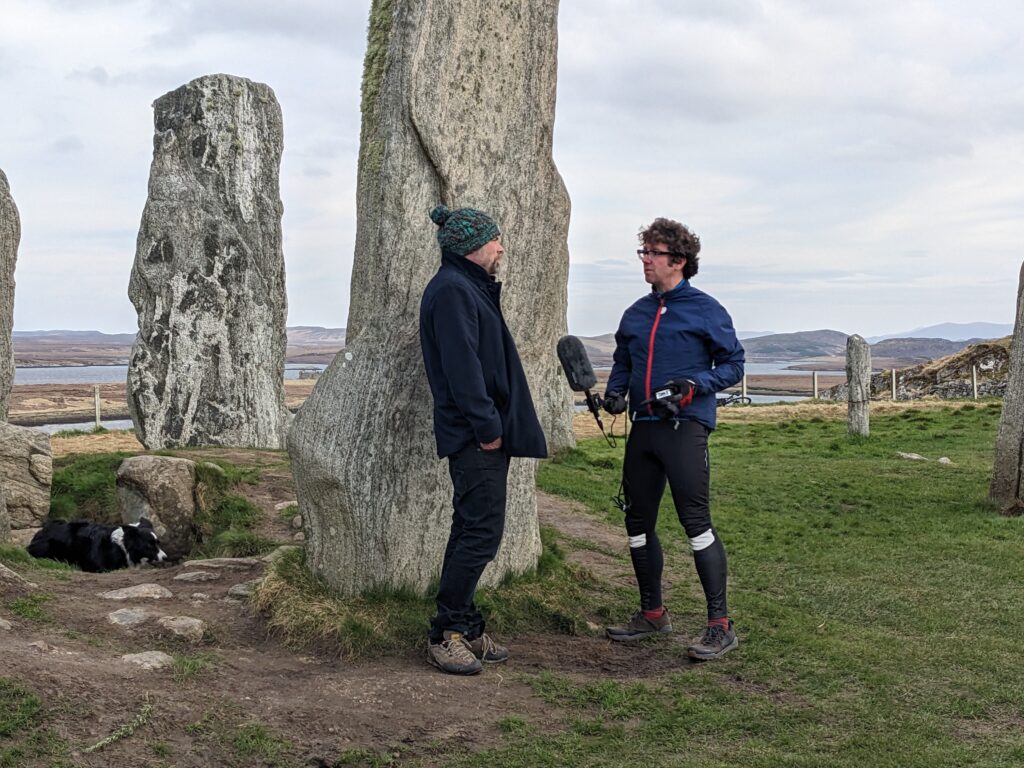 Person being interviewed in front of large standing stones