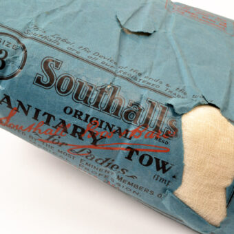 Photo of an early 20th-century sanitary towel, in a blue paper package with the words "Southall Sanitary Towel" printed in black on the front